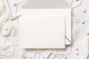 Blank card near white decorations, pebbles and silk ribbons top view, wedding menu mockup