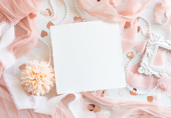 Card near pink decorations, hearts and silk ribbons on white table top view, mockup