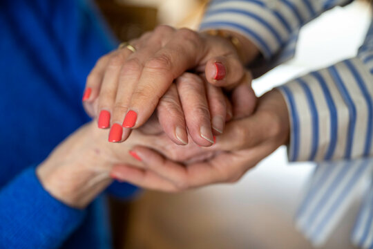 two elderly ladies holding hands close up
