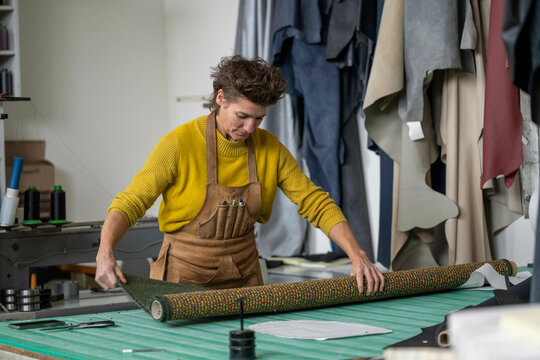 Nederland - Illustratief beeld. Meubelstoffeerder in haar werkplaats. Op de werkbank ligt stof op de rol en achter haar hangen stukken leer. foto: ANP / Hollandse Hoogte / Patricia Rehe