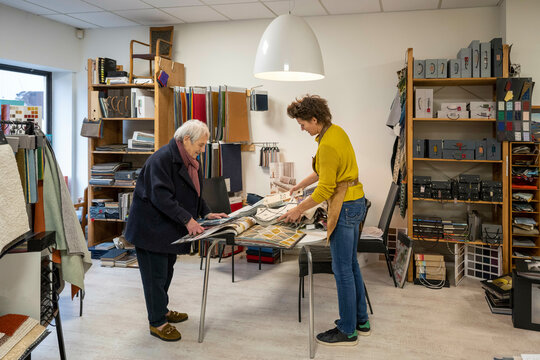 Female upholstery helping client select fabric
