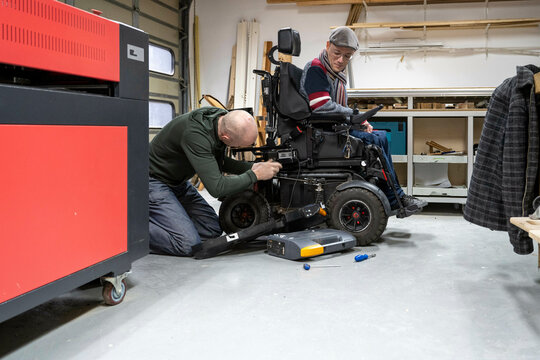 Mechanic working on mans prototype wheelchair 
