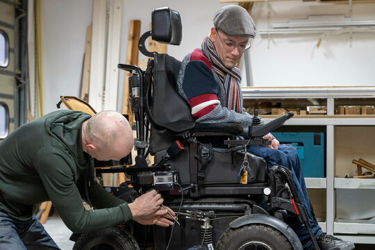 Mechanic working on mans prototype wheelchair 