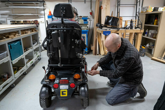 Mechanic working on mans prototype wheelchair 