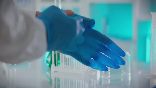 Pharmacology. A researcher is concentrating on putting on nitrile gloves in the laboratory. Camera movement professional worker puts on protective gloves using modern technology, doctor