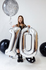 A little girl celebrates her 10th birthday. A girl on a white background in a black dress with long straight hair. Party, holiday