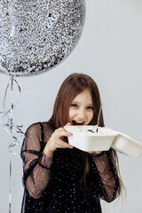 A little girl celebrates her 10th birthday. A girl on a white background in a black dress with long straight hair. Party, holiday