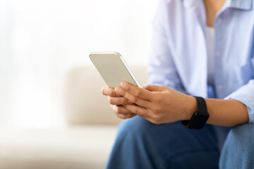 Cropped of lady enjoying weekend at home, using smartphone