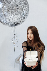 A little girl celebrates her 10th birthday. A girl on a white background in a black dress with long straight hair. Party, holiday