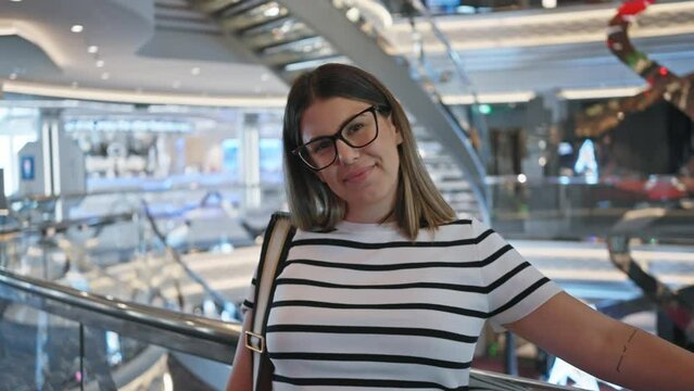 Smiling woman with glasses aboard a modern luxury cruise ship interior posing for a vacation portrait.