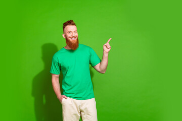 Photo of optimistic man with ginger beard dressed green t-shirt indicating at offer empty space...