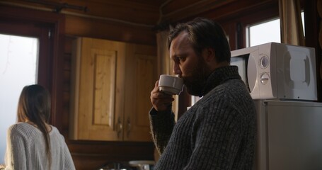 Multiethnic tourist friends drink coffee together in holiday house kitchen. Big travelers family stopped to rest in wooden cottage during vacation trip. Tourism and active leisure concept. Close up.