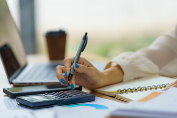 Close-up portrait of businesswoman accountant using calculator and laptop for matching financial data saving in office room, Business financial, tax, accounting concept.