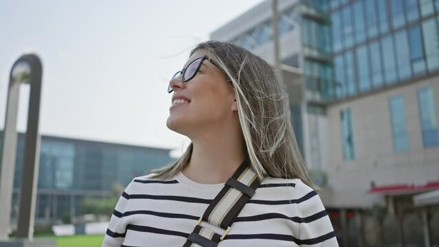 Smiling woman in glasses enjoying sights in a modern cityscape setting, indicating leisure travel and urban exploration.
