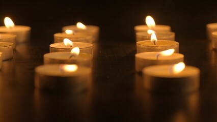 Burning candles. The candles burn against a black background and the flames move when the wind...
