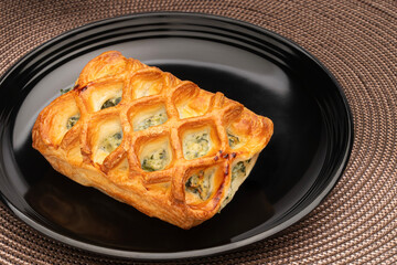 Baked spinich and cheese pastry on a black plate