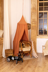 Rustic playroom interior with rattan crib with canopy, wicker baskets, toys and window. Wickered cradle bed with baldachin in newborn room in scandi style at home. Black racing car toy in a child room © stock_studio