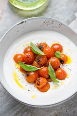 Bowl of greek feta dip with roasted cherry tomatoes and basil, middle close-up, vertical shot, selective focus