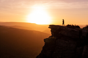 silhouette of a person standing on a rock sunset