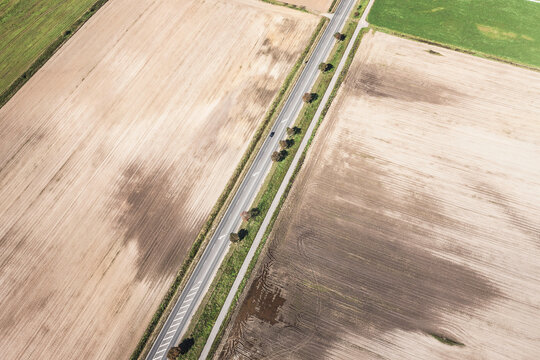 Aerial view of road through countryside with fields on both sides.