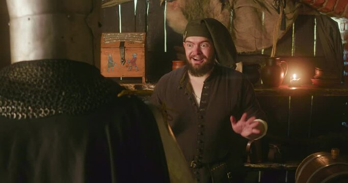 Merchant happy to serve knight in store. Smiling obese dwarf with beard sells goods to honorable warrior in medieval tavern. Role-play reconstruction