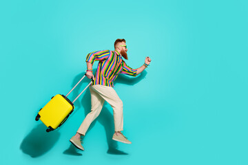 Full body length photo of running man tourist with yellow suitcase empty space hurry up to airport isolated on cyan color background