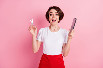 Photo portrait of amazed hairdresser keeping scissors brush isolated pastel pink color background