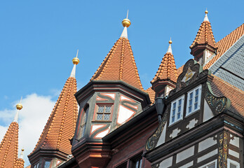 Fototapeta na wymiar Roof towers and part of the half-timbered front gable of the Old Town Hall in Fulda, Germany, with blue sky on a summer afternoon