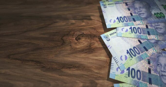 South Africa Rand banknotes on the wooden table. South African 100 ZAR currency paper notes 3D concept background. Seamless and looped.