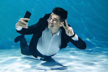 A man calls on the phone while he is at the bottom underwater. Creative concept