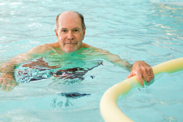 Older senior gentleman swimming and doing water gymnastics in a pool. Munich, Germany