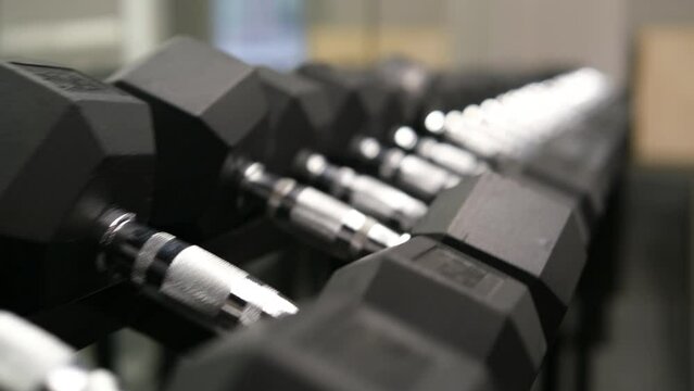 4K view of Dumbbell sets, Fitness gym boasts impressive collection dumbbells and expert-level workout gear. Sport gear. Close up, slow motion
