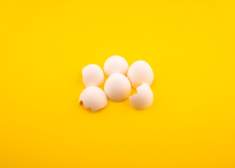 broken chicken egg shells on yellow background. broken white chicken egg shells