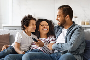 Smiling african american family having great time at home, watching tv together