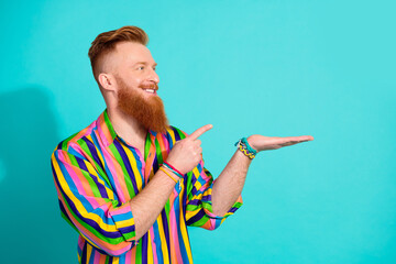 Photo of irish man promoter in striped shirt direct finger to his hand object miniature funko pop toy isolated on cyan color background