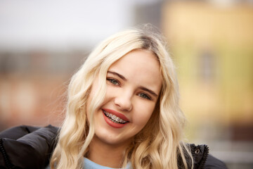 Naklejka premium Portrait of cheerful smiling woman with dental braces looking at camera against blurred background. Urban lifestyle. Concept of youth and healthcare, medicine and beauty, confidence and selfcare
