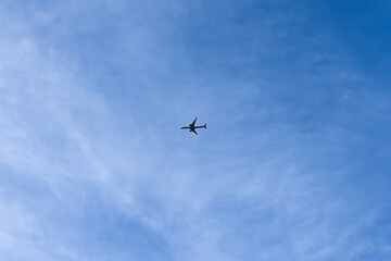 London, UK, 25 January 2024: Airplane flying in the blue sky among clouds and sunlight