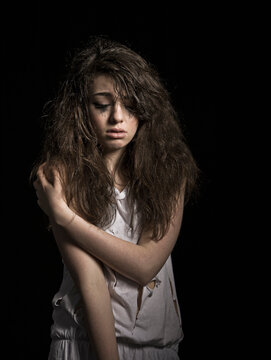 Studio portrait of depressed sad girl with black background.