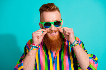 Photo of handsome red hair guy in sunglass fixing his well groomed mustache barber shop advertisement isolated on cyan color background - obrazy, fototapety, plakaty