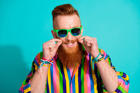 Photo of handsome red hair guy in sunglass fixing his well groomed mustache barber shop advertisement isolated on cyan color background