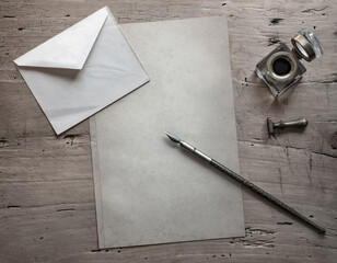 Old Fountain pen, quill pen, postal envelope, old paper blank sheet and vintage inkwell on wooden desk in the old office . Retro style. Conceptual background on history, education, literature topics.