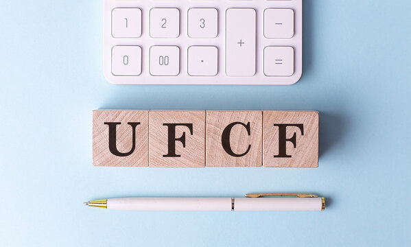UFCF UNVERED FREE CASH FLOW on wooden cubes with pen and calculator, financial concept