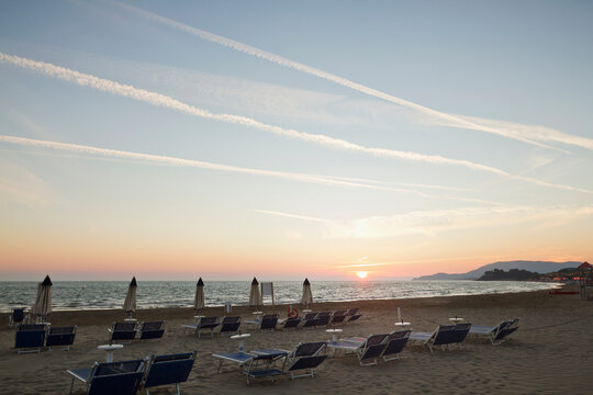 Sunset over a beach with sun chairs and umbrellas closed, Italy