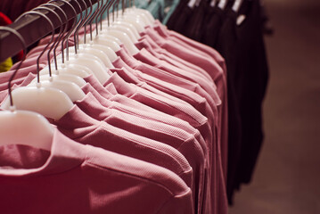 Colorful pink outerwear on hangers in a clothing store close-up, soft selective focus.