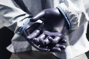 Hands of a plastic mannequin in a light shirt on a clothing store window close-up, soft focus