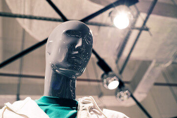 Close-up portrait of a faceless modern mannequin in a white jacket on a clothing store window, soft focus.