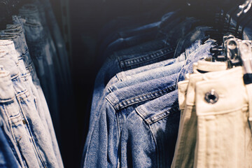 Denim jackets and trousers on hangers in a supermarket close-up, selective soft focus