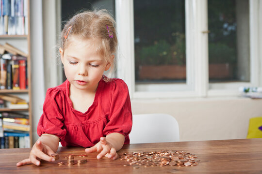 Young girl counting pennies on the table.