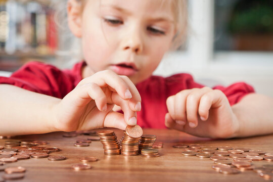 Young girl counting pennies on the table.