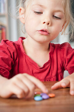 Young girl counting smarties on a table. Munich, Germany